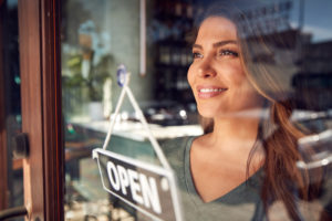 Independent business owner standing in her own coffee shop, weighing starting a business against buying a franchise